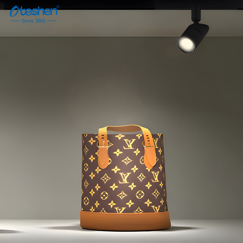 Single magnetic track cylinder spotlight illuminating luxury handbag in showroom Көрме залындағы сәнді сөмкені жарықтандыратын жалғыз магнитті цилиндрлі прожектор