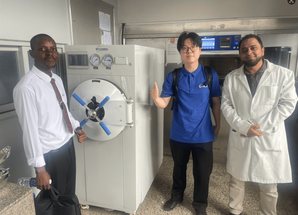Il team MeCanMed ispeziona un grande sterilizzatore autoclave orizzontale ad alta temperatura con il personale clinico in una clinica dello Zambia.