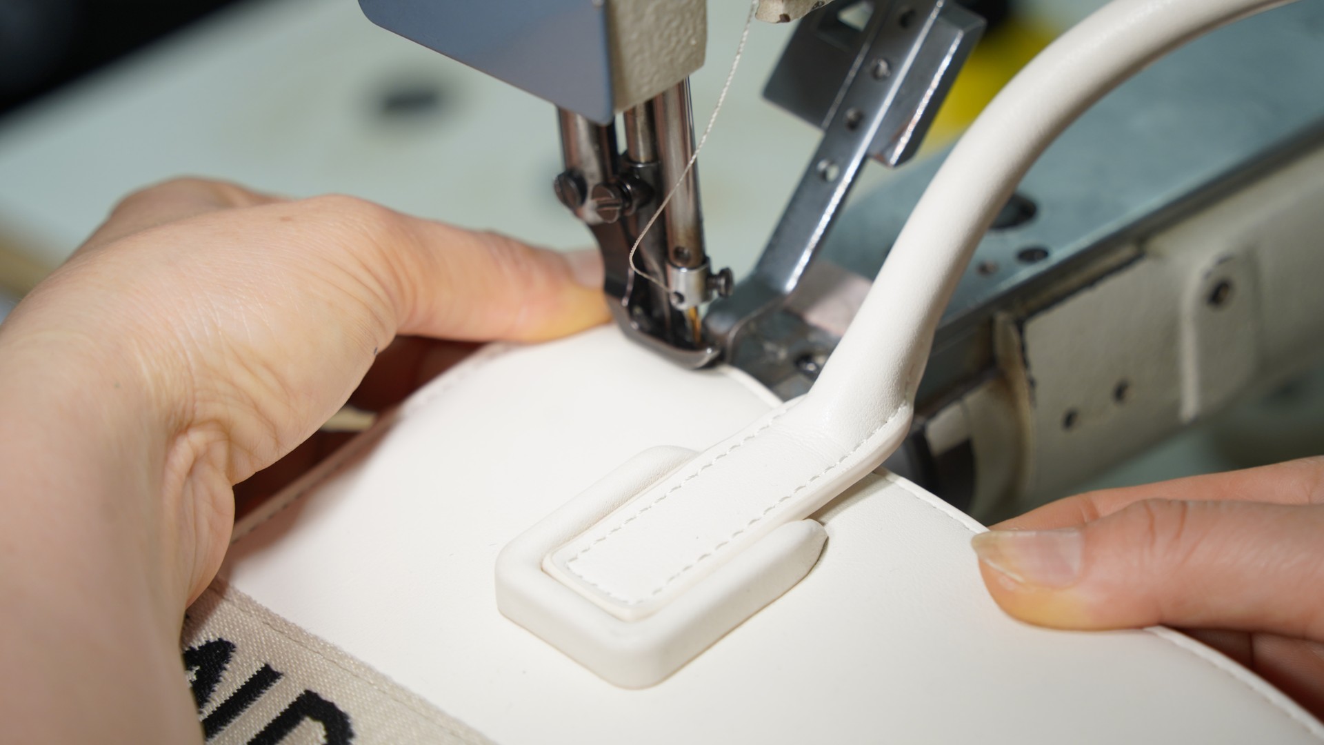 Artisan hand-stitching a leather shoulder bag reinforcement